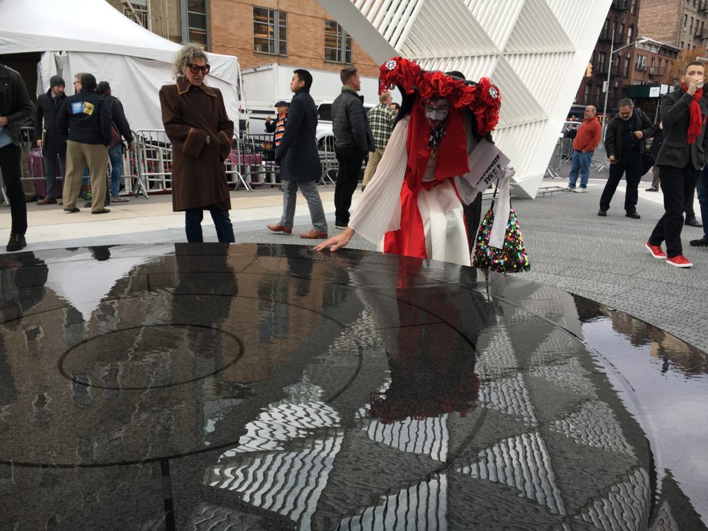 A visitor to the AIDS Memorial gently touches and experiences the water fountain feature at the Memorial as light reflects the triangular patterns on the water. 